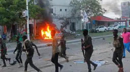 Petugas berjalan di dekat mobil yang terbakar setelah sebuah serangan bom mobil di sebuah restoran di Mogadishu, Somalia, (8/5). Setidaknya 6 orang tewas dan 10 orang lainnya terluka dalam serangan bom mobil tersebut. (AP Photo/Farah Abdi Warsameh)