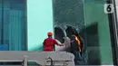 Petugas memecahkan kaca saat berusaha memadamkan kebakaran di Gedung Cyber 1, Jakarta, Kamis (2/12/2021). Suku Dinas Pemadam Kebakaran DKI Jakarta menurunkan 22 unit mobil pemadam kebakaran. (Liputan6.com/Herman Zakharia)