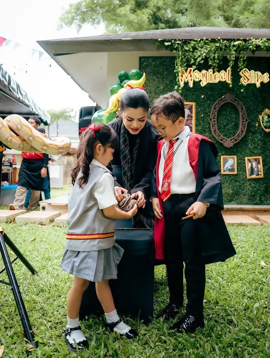 Sementara itu, adik Xabiru, Chava, tampil tidak kalah memikat. Chava mengenakan seragam vest abu-abu dengan aksen merah dan emas yang mencirikan salah satu asrama di Hogwarts. Paduan rok abu-abu, kemeja putih, dan sepatu hitam menambah kesan lucu namun tetap serasi dengan tema acara. [@vienstasman]