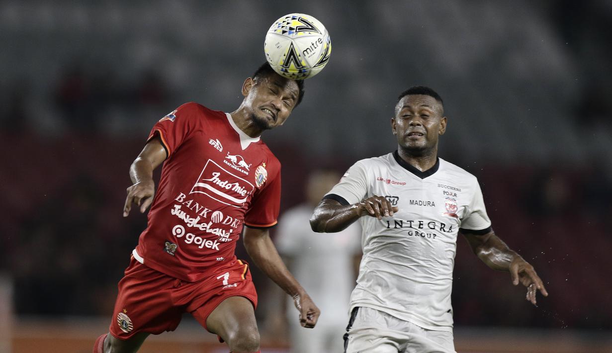 Gelandang Persija Jakarta, Novri Setiawan, berebut bola atas dengan striker Madura United, Beto Goncalves, pada laga Shopee Liga 1 di SUGBK, Jakarta, Jumat (13/12). Persija menang 4-0 atas Madura. (Bola.com/Yoppy Renato)