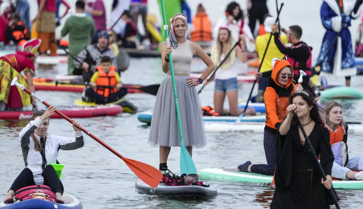 Orang-orang mengarahkan papan SUP mereka selama festival dayung berdiri (stand up paddle) di kanal dayung Olimpiade Krylatskoye, Moskow, Rusia, Minggu (12/9/2021). Selain menjadi agenda rutin pariwisata, kegiatan tersebut juga dimaksud untuk memopulerkan SUP ke masyarakat luas. (AP/Pavel Golovkin)
