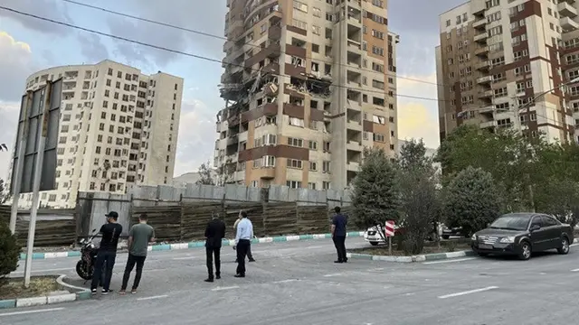 Warga mengamati apartemen yang rusak di Teheran, Iran, akibat serangan udara Israel pada Jumat (13/6/2025).