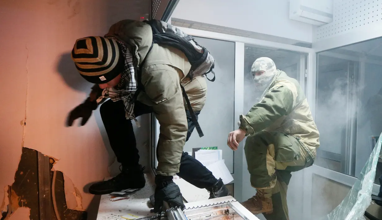 Dua orang demonstran saat merusak seisi bank Rusia, Sberbank di Kiev, Ukraina (21/11). Aksi dilakukan untuk memperingati tragedi kerusuhan 2014 yang menyebabkan lebih dari 100 warga Ukraina tewas. (REUTERS/Valentyn Ogirenko)