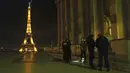 Polisi memeriksa seseorang selama jam malam di Trocadero, dekat Menara Eiffel, Paris, Perancis, Selasa (15/12/2020). Para pejabat telah memperingatkan bahwa mereka akan menegakkan peraturan baru dengan ketat. (AP Photo/Francois Mori)