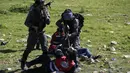 Tentara Israel menodongkan senjata ke petugas medis Palestina ketika berusaha mengobati demonstran yang terlibat bentrokan di Ramallah, Tepi Barat, Senin (12/3). Aksi protes terkait pengangkapan salah satu mahasiswa oleh pasukan Israel. (ABBAS MOMANI/AFP)