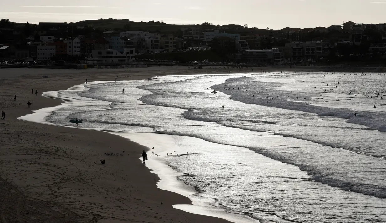 Peselancar menikmati air di Pantai Bondi di Sydney, Selasa, (28/4/2020). Pantai dibuka kembali setelah sempat ditutup selama 6 minggu untuk mencegah penyebaran corona (COVID-19). (AP Photo/Rick Rycroft)