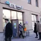 Orang-orang antre menarik uang dari ATM Bank VTB di pusat kota Moskow, 28 Februari 2022. Anjloknya nilai mata uang Rusia, rubel, dalam perdagangan menyusul sanksi terkait invasi di Ukraina membuat warga ramai-ramai mendatangi ATM hingga bank untuk menarik uang tunai mereka. (AP Photo/Pavel Golovkin)