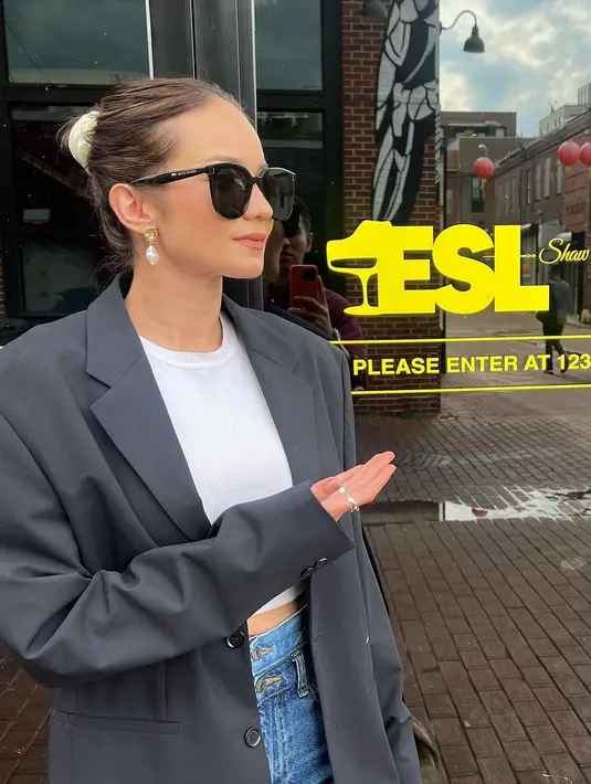 Gaya stylish Enzy Storia memadukan cropped top putih dan celana jeans. Penampilannya ini disempurnakan dengan blazer abu-abu, rambut dicepol atas, dan sunglasses. [Foto: Instagram/enzystoria]