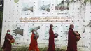 Biksu Buddha mengenakan masker berjalan melewati papan peringatan COVID-19 saat mereka mengumpulkan sedekah pagi di Yangon, Myanmar, Kamis (15/7/2021). Hampir 90 persen wilayah di Myanmar telah terkena dampak gelombang ketiga Covid-19. (AP Photo/Thein Zaw)