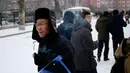 Seorang pria mengisap  rokok saat melintasi jalanan tertutup salju di Pyongyang, Korea Utara Minggu (16/12). Korea Utara saat ini mulai memasuki musim dingin. (AP Photo/Dita Alangkara)