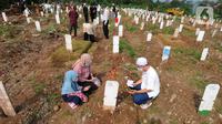 Warga berziarah dengan latar belakang pemakaman korban Covid-19 di TPU Srengseng Sawah 2, Jagakarsa, Jakarta, Senin (17/5/2021). Hari ini seluruh TPU di wilayah DKI dibuka untuk umum dengan menerapkan protokol kesehatan seperti pembatasan pengunjung dan waktu berziarah. (merdeka.com/Arie Basuki)