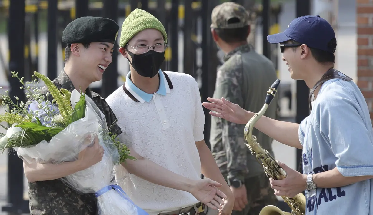 RM memainkan lagu “Dynamite” dengan saksofon, sementara Jin tersenyum lebar melihat aksi sahabatnya.  (Im Byung-shik/Yonhap via AP)