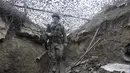 Tentara Ukraina berjalan di bawah jaring kamuflase di parit di garis pemisah dari pemberontak pro-Rusia dekat Debaltsevo, wilayah Donetsk, Ukraina (3/12/2021). Ukraina mengklaim Rusia telah mengirim lebih dari 94 ribu personel ke perbatasan. (AP Photo/Andriy Dubchak)
