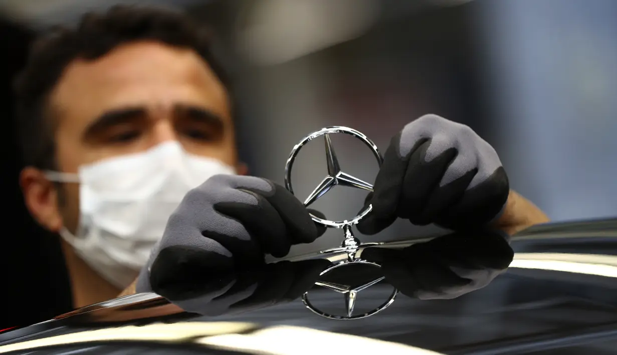 Karyawan menempelkan lambang saat merakit mobil Mercedes-Benz S-class di pabrik Mercedes, Sindelfingen, Jerman, Kamis (30/4/2020). Mulai 27 April 2020, Mercedes-Benz kembali membuka jalur produksi yang sebelumnya ditutup karena pandemi virus corona COVID-19. (AP Photo/Matthias Schrader)