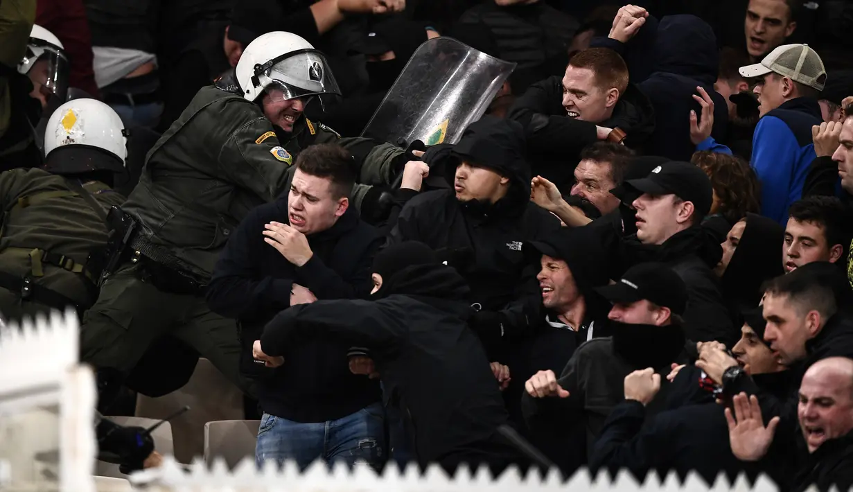 Suporter Ajax Amsterdam bentrok dengan polisi anti huru-hara Yunani sebelum pertandingan Liga Champions melawan AEK Athena di Stadion Olimpiade Athena, Selasa (27/11). Lemparan bom molotov juga mewarnai kerusuhan di stadion itu. (Aris Messinis/AFP)