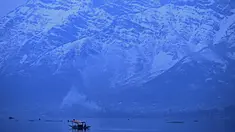 Orang-orang menikmati perjalanan dengan perahu dengan latar belakang pegunungan yang tertutup salju di danau Dal di Srinagar (11/1/2022). Danau Dal yang merupakan danau terbesar kedua di propinsi Jammu dan Kashmir negara bagian India ini merupakan pusat pariwisata dan rekreasi. (AFP/Tauseef Mustafa)