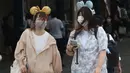 Pengunjung mengenakan masker guna melindungi diri dari virus corona berjalan menuju pintu masuk Tokyo Disneyland di Urayasu, dekat Tokyo, Rabu (1/7/2020). Tokyo Disneyland dibuka kembali untuk pertama kalinya dalam empat bulan setelah sempat ditutup karena penyebaran Covid-19. (AP/ Koji Sasahara)