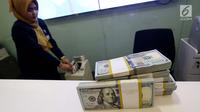 Petugas bank menghitung uang dollar AS di Jakarta, Jumat (20/10). Nilai tukar Rupiah terhadap Dolar Amerika Serikat (USD) masih belum beranjak dari level Rp 13.500-an per USD. (Liputan6.com/Angga Yuniar)