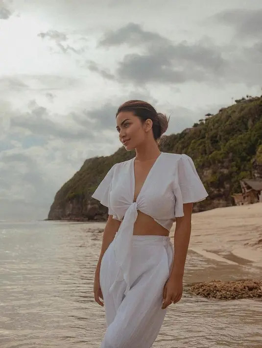 Simple tapi stylish, kali ini Ariel Tatum tampil serba putih memadukan wrap crop top dengan loose pants warna senada.  (Instagram/arieltatum/anaditya_).