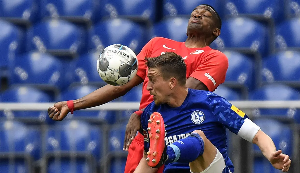 Pemain Augsburg, Felix Uduokha berebut bola dengan Schalke 04, Bastian Oczipka, pada laga Bundesliga di Veltins-Arena, Minggu (24/5/2020). Augsburg menang dengan skor 3-0 atas Schalke 04. (AP/Martin Meissner)