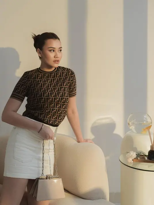 Gaya slay cantik ala Aaliyah Massaid dengan baju satu set dari FENDI. Ia mengenakan atasan lengan pendek berwarna cokelat dengan corak logo brand FENDI, dipadunya dengan mini skirt berwarna putih gading. [Foto: Instagram/aaliyah.massaid]