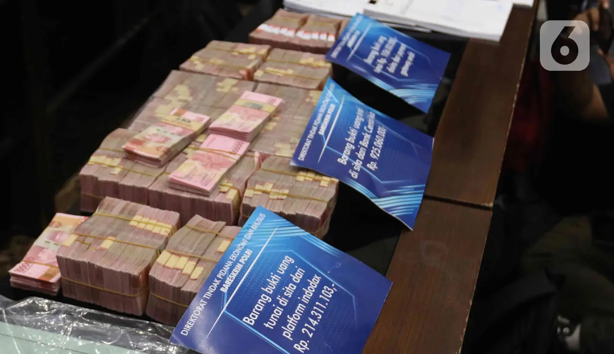 Barang bukti berupa tumpukan uang tunai dalam kasus Binomo dengan tersangka Indra Kesuma alias Indra Kenz di Mabes Polri, Jakarta, Jumat (25/3/2022). Barang bukti tersebut mulai dari tumpukan uang tunai yang jumlahnya miliaran hingga satu unit mobil tesla berwarna biru (Liputan6.com/Herman Zakharia)