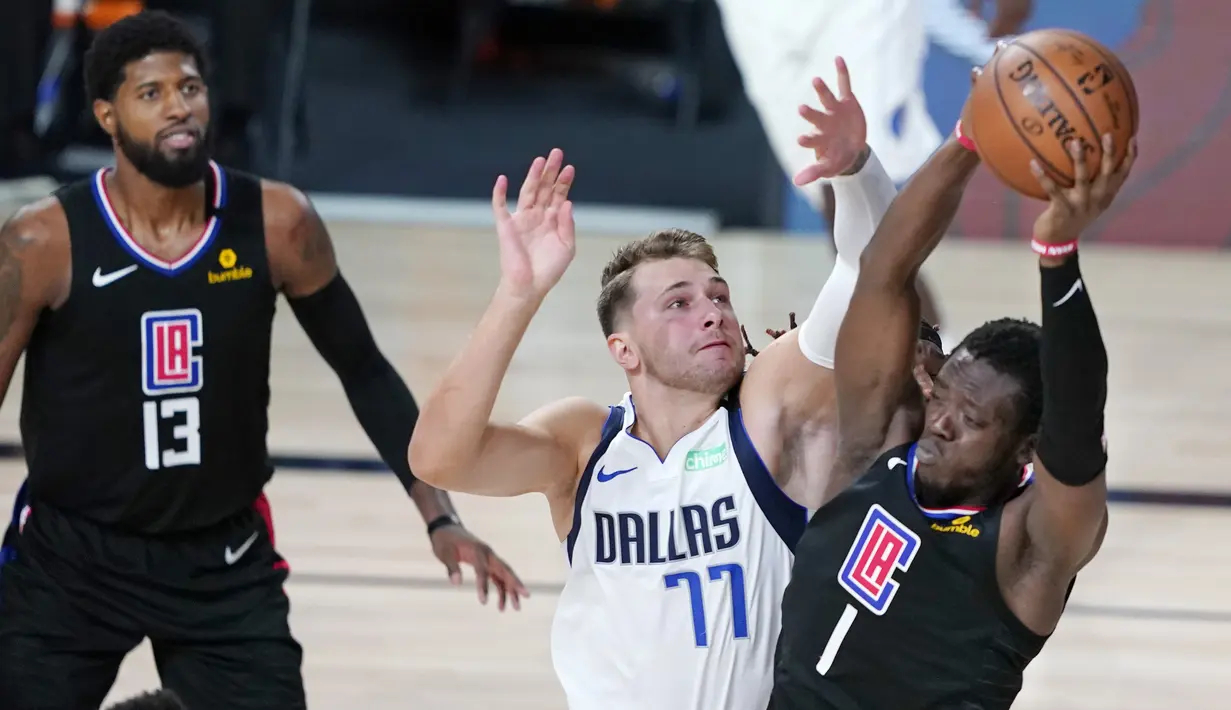 Pebasket Dallas Mavericks, Luka Doncic, berebut bola dengan pemain Los Angeles Clippers, Reggie Jackson, pada gim kedua playoff NBA 2020 di AdventHealth Arena, Kamis (20/8/2020). Maverick menang 127-114 atas LA Clipppers. (AFP/Ashley Landis-Pool/Getty Images)