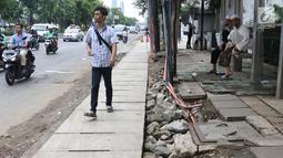 Pejalan kaki melintasi bekas galian gorong-gorong di Jalan Hayam Wuruk, Jakarta, Rabu (20/2). Tidak maksimalnya perbaikan pascapembongkaran gorong-gorong menyebabkan trotoar di kawasan itu dipenuhi kerikil serta batu. (Liputan6.com/Immanuel Antonius)