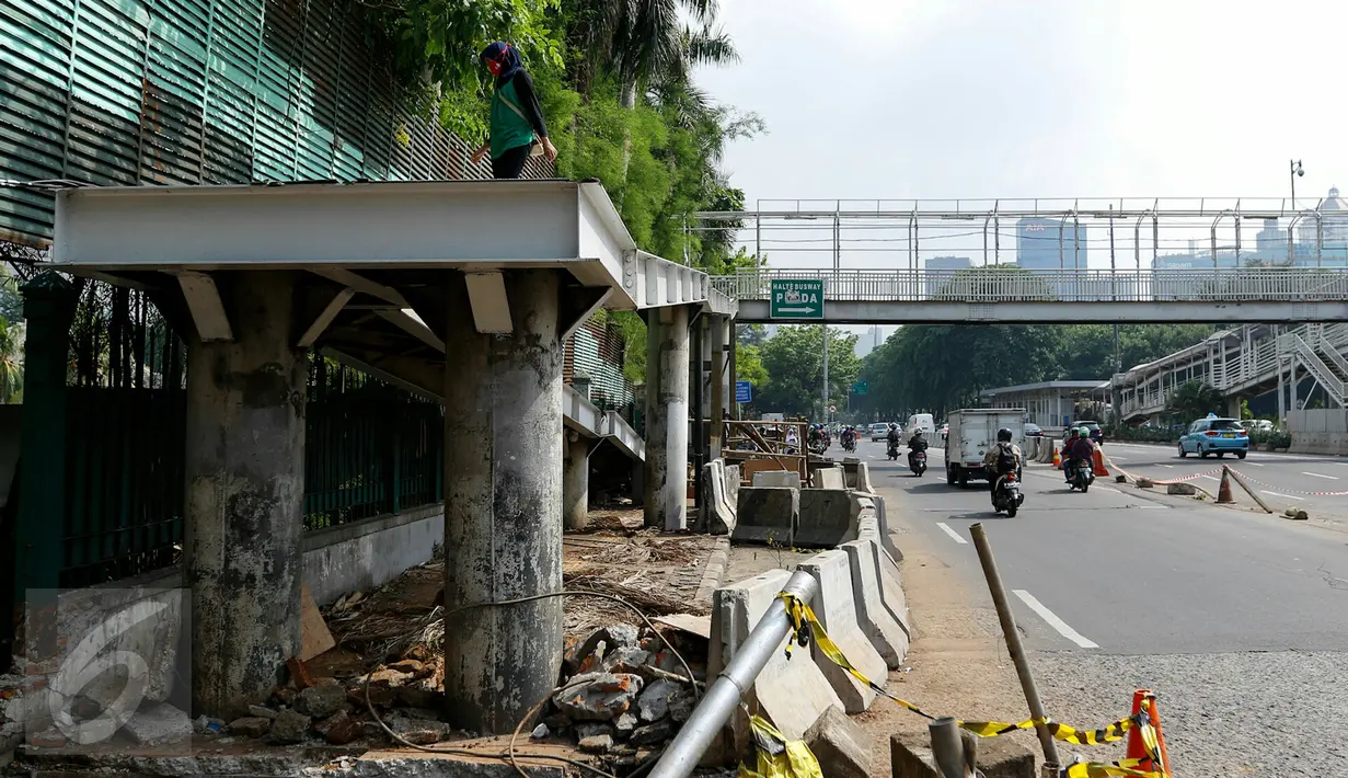 Warga melewati JPO sisi barat Polda Metro Jaya di Jalan Jenderal Sudirman, Jakarta, meski sudah ditutup dan dibongkar, Senin (23/11). Pembongkaran dilakukan karena pekerjaan konstruksi bawah tanah untuk perbaikan saluran air. (Liputan6.com/Yoppy Renato)