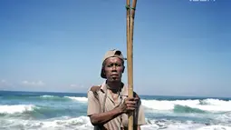 Marsiono, berpose memegang sebilah bambu untuk mencari undur-undur atau yutuk di bibir Pantai Bocor, Kabupaten Kebumen, Jawa Tengah, Sabtu (05/5). Aktivitas tersebut telah berjalan puluhan tahun. (Liputan6.com/Fery Pradolo)