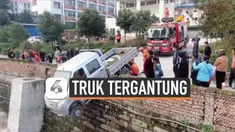 Petugas pemadam kebakaran menyelamatkan seorang sopir terjebak di dalam truk yang tergantung di dinding bata setinggi 3,9 meter. Insiden bermula dari truk yang hilang kendali dan menabrak dinding.