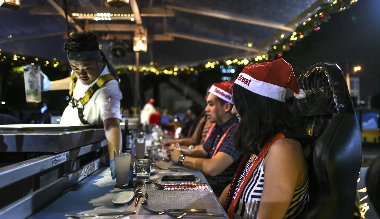 Pelayan melayani pengunjung restoran gantung dengan dekorasi kereta salju santa claus di Kuala Lumpur, Malaysia, Rabu (5/12). Pengunjung ditawarkan sensasi bepergian dengan kereta salju santa claus lengkap dengan rusa. (MOHD RASFAN/AFP)