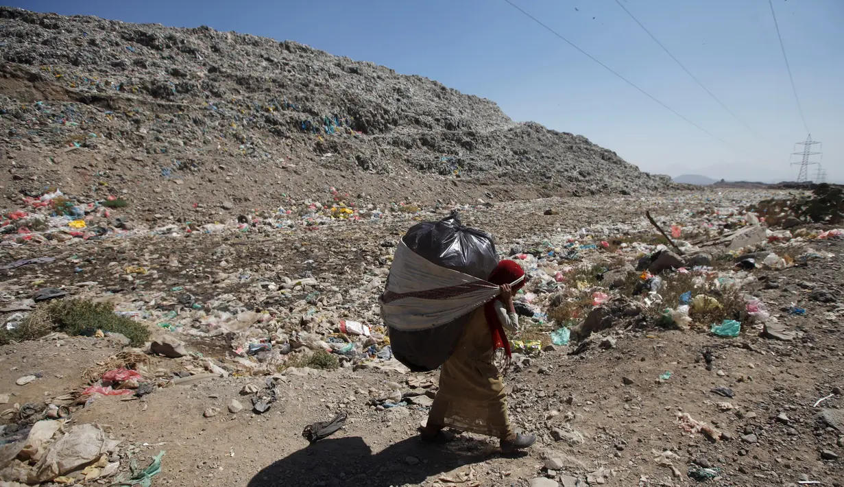 Bocah perempuan menggendong plastik besar berisi sampah di sebuah tempat pembuangan akhir (TPA) di pinggiran Sanaa, Yaman, Rabu (16/11). Setiap hari para bocah di daerah itu mengumpulkan sampah untuk didaur ulang atau dijual. (REUTERS/Mohamed al-Sayaghi)