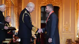 Mantan pesepak bola, David Beckham (kanan) berjabat tangan dengan Raja Inggris, Charles III setelah upacara penobatan gelar Ksatria di Kastil Windsor, Berkshire, Inggris, Selasa (04/11/2025) waktu setempat. (AP Photo/PA/Jonathan Brady)