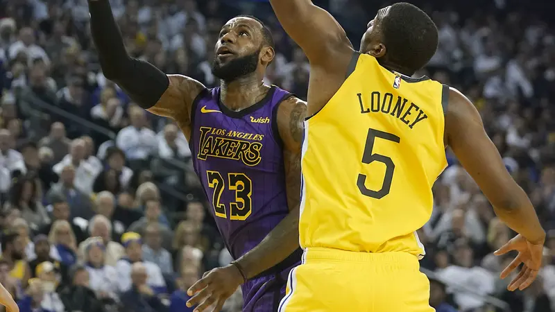 Bintang LA Lakers, LeBron James (kiri) diadang pemain Golden State Warriors, Kevon Looney