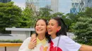 Pada momen lainnya, mereka tampak menikmati suasana sore hari dari atas rooftop, tetap dengan tampilan yang stylish. Kali ini, Hanggini memilih tampilan preppy style, dengan perpaduan white sweater dan mini pleated skirt. Ia pun mengenakan tas yang sama seperti Shenina di tampilan sebelumnya namun dalam warna berbeda, yaitu Grace East-West Shoulder Bag berwarna taupe.  [Kate Spade]