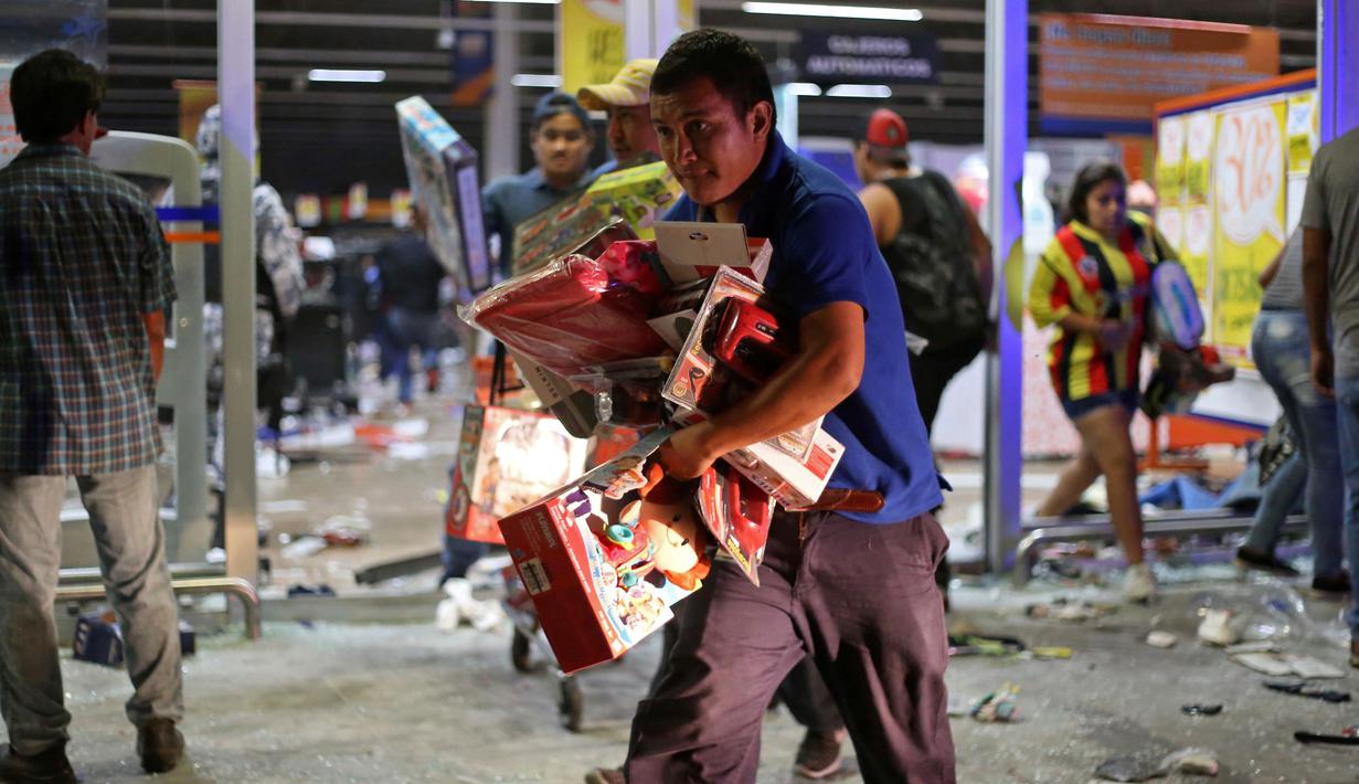 Seorang warga Meksiko membawa mainan saat menjarah toko di pelabuhan Veracruz, Meksiko, (4/1). Keputusan pemerintah Meksiko menaikkan harga Bahan Bakar Minyak hingga 20 persen per tanggal 1 Januari 2017 memicu amarah warganya. (AP Photo/Ilse Huesca)