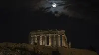 Bulan purnama terakhir tahun ini yang dikenal sebagai bulan dingin muncul di atas kuil kuno Parthenon saat hari mendung, di Athena, Yunani, Rabu (7/12/2022). Bulan purnama Desember sendiri dikenal sebagai Cold Moon atau Bulan Dingin. (AP Photo/Petros Giannakouris)