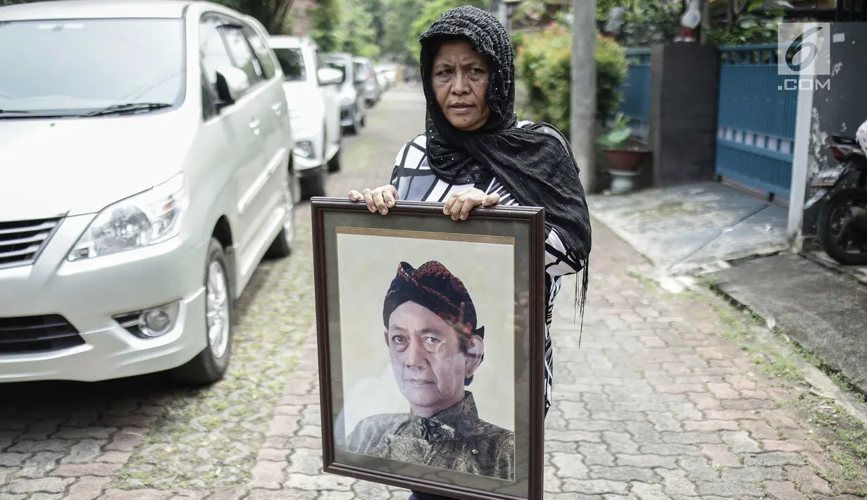 Seorang wanita memegang foto aktor senior Deddy Sutomo di dekat rumah duka kawasan Rempoa, Tangerang Selatan, Rabu (18/4). Selain berakting, Deddy Sutomo sempat menjadi anggota legislatif DPR RI komisi X periode 2004-2009. (Liputan6.com/Faizal Fanani)