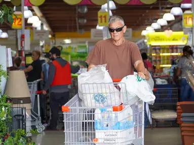 Seorang pria membeli perbekalan dan makanan yang tidak mudah rusak di supermarket sebagai persiapan menghadapi datangnya Badai Tropis Ernesto, di San Juan, Puerto Riko, Selasa (13/8/2024). (Jaydee Lee SERRANO / AFP)