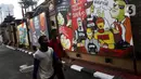 Warga melintas di depan mural berisi kritik terhadap kinerja polisi di Lapangan Bhayangkara Mabes Polri, Jakarta, Minggu (31/10/2021). Lomba mural 2021 Piala Kapolri menampilkan sejumlah karya berisi kritik terhadap polisi yang dituangkan pada media triplek. (Liputan6.com/Helmi Fithriansyah)