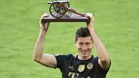 Striker Bayern Munchen Robert Lewandowski memegang trofi pencetak gol terbanyak musim ini setelah memenangkan gelar Bundesliga di stadion Allianz Arena, Sabtu, 22 Mei 2021. (Sven Hoppe , Pool via AP)