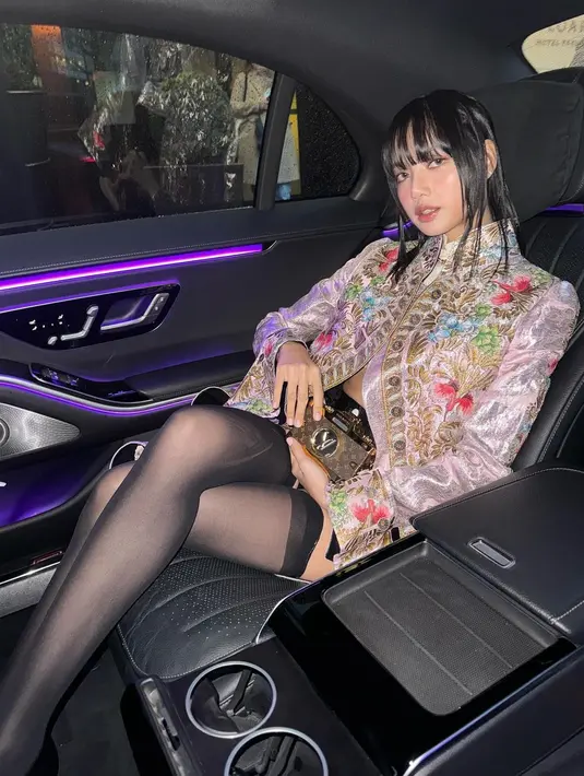 Lisa membiarkan mantel panjangnya tidak dikancing, sehingga crop top putih dan kalung liontinnya terlihat. [Foto: Instagram/lalalalisa_m]