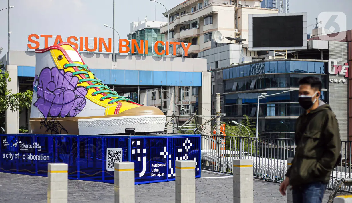 Pejalan kaki berjalan di depan Tugu Sepatu, Sudirman, Jakarta, Minggu (19/9/2021). Tugu Sepatu menjadi sasaran pencoretan dengan semprotan aerosol oleh orang tak dikenal sehari usai diresmikan pada 17 September 2021. (Liputan6.com/Faizal Fanani)