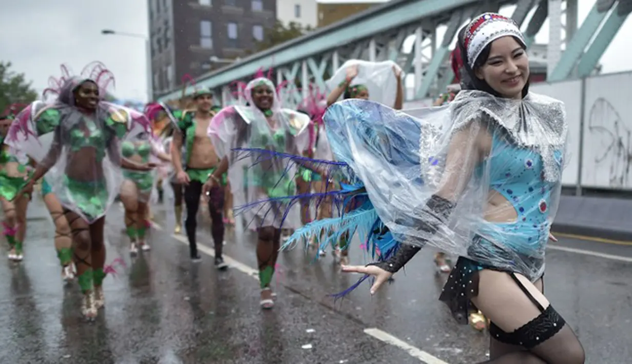 Para penari tampil mengenakan mantel plastik saat beraksi di tengah hujan dalam karnaval Notting Hill, London, Inggris (31/8/2015). Karnaval Notting Hill diadakan untuk merayakan budaya Karibia yang sudah dikenal sejak 1960-an. (AFP PHOTO/LEON Neal)