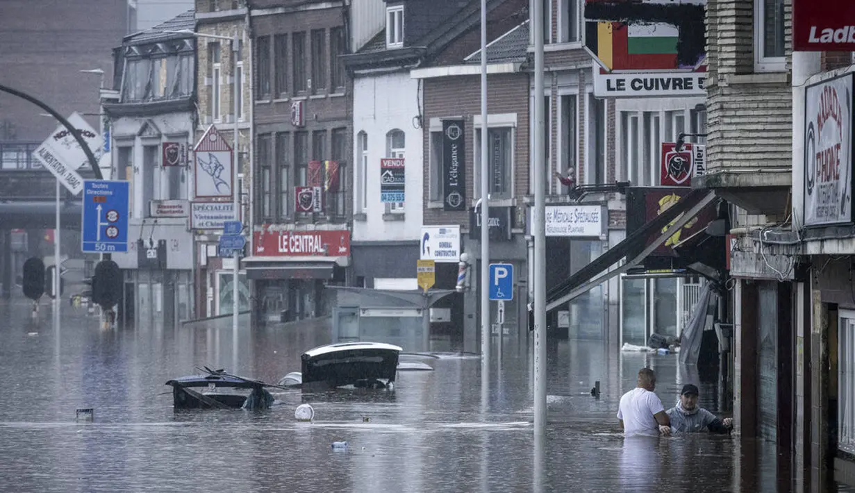 Dua orang berdiri di genangan air setelah Sungai Meuse meluap saat banjir besar di Liege, Belgia, Kamis (15/7/2021). Banjir melanda sejumlah negara di kawasan Eropa barat. Selain Belanda dan Jerman, banjir juga menerjang Belgia. (AP Photo/Valentin Bianchi)