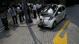 Awak media saat melihat kendaraan self-driving otonom pada demonstrasi di sebuah taman Singapura, Senin (12/10). Mobil dan bus di jalanan tanpa sopir ini sudah menjadi program panjang Singapura untuk menciptakan kendaraan umum autopilot.(REUTERS/Edgar Su)