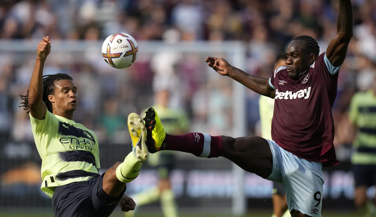 Bek Manchester City, Nathan Ake berebut bola dengan pemain West Ham, Michail Antonio pada pertandingan pembuka Liga Inggris 2022/2023 di Stadion London di London, Inggris, Senin (8/8/2022). City menang atas West Ham 2-0.  (AP Photo/Frank Augstein)