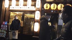 Orang-orang yang mengenakan masker untuk membantu melindungi diri dari penyebaran virus corona berjalan di sepanjang jalan yang dipenuhi bar dan restoran di Tokyo, Selasa (22/3/2022). Langkah-langkah pra-darurat untuk mencegah wabah Covid-19 telah dicabut. (AP Photo/Koji Sasahara)