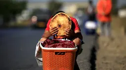 Issaac (8), memegang sepotong roti tradisional yang dijajakannya di tepi jalan raya di pinggiran Algiers, Aljazair, 13 Juni 2016. Selama bulan Ramadan, sejumlah anak membantu orangtuanya menjajakan roti di kawasan ini. (REUTERS/Zohra Bensemra)